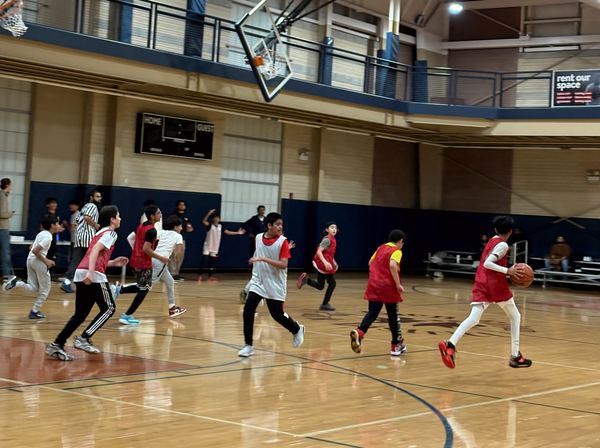 A boys basketball game with a referee and families watching.